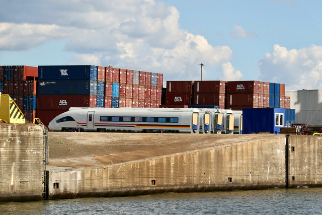 A rail car beside stacked freight containers at a terminal.