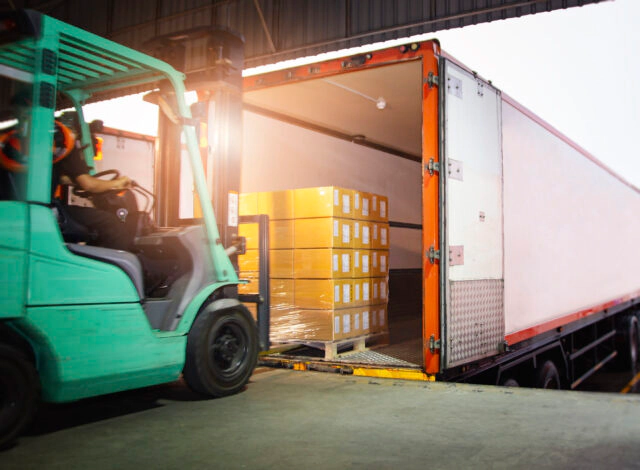 A forklift moving cartons into a truck trailer.
